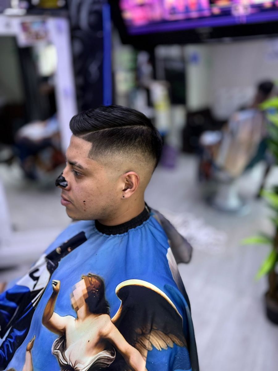 Fade con raya marcada y peinado hacia atrás